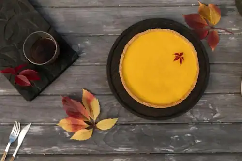 Top down view of a delicious pumpkin pie with autumn leaves on a rustic table. 5662127 scaled